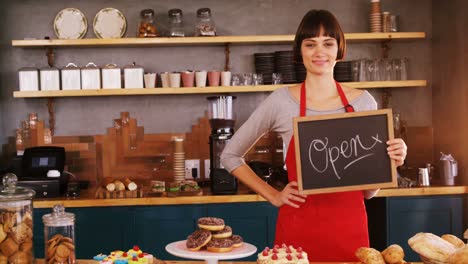 Smiling-waitress-showing-a-open-sign-board