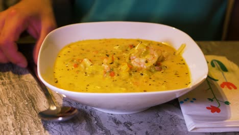 eating healthy fish soup with wild atlantic prawns in a white bowl - close up