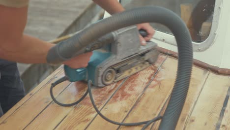 Belt-sanding-roof-planks-of-wood-boat-using-belt-sander