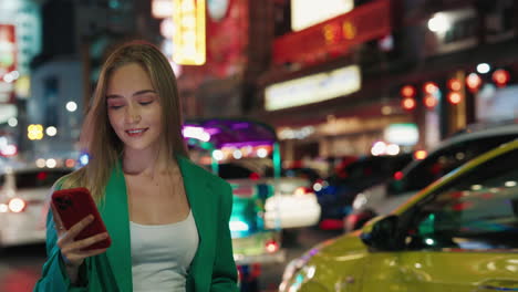 woman using phone in a busy city street at night