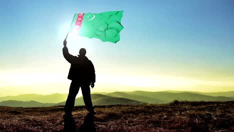 hombre ganador de silueta exitosa agitando la bandera de turkmenistán en la cima de la montaña, fondo de bucle de cinemagraph