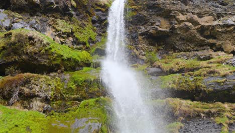 Vögel-Fliegen-über,-Während-Wasser-Auf-Das-Grüne-Moos-Fällt-Und-Einen-Wasserfall-Bildet