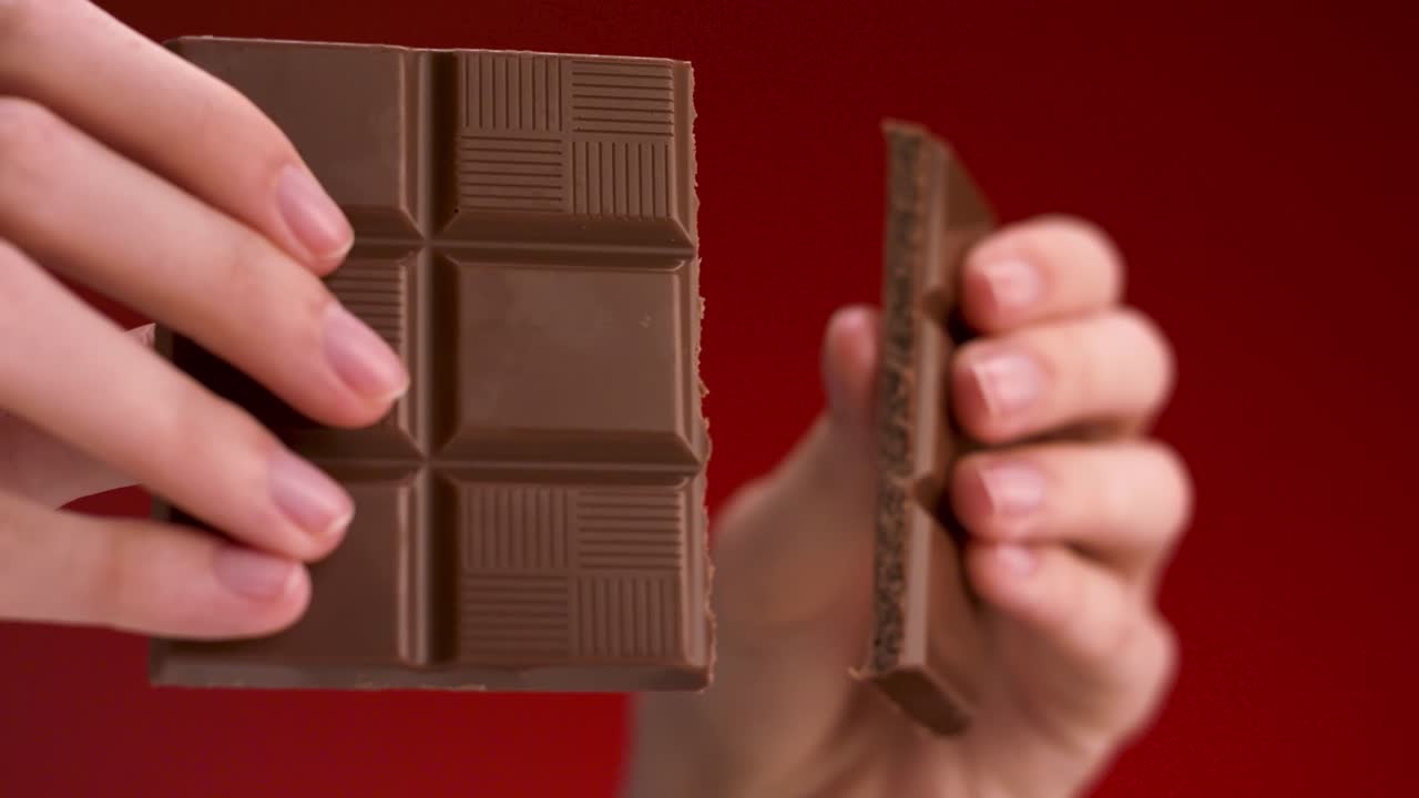 una mujer rompiendo una barra de chocolate.