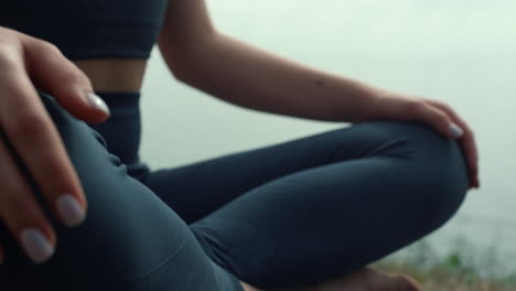 fit girl practicing lotus pose on sea beach closeup. woman hand lie on knees