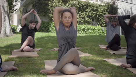 Gente-Sentada-En-Colchonetas-De-Yoga-Y-Practicando-Yoga-Al-Aire-Libre