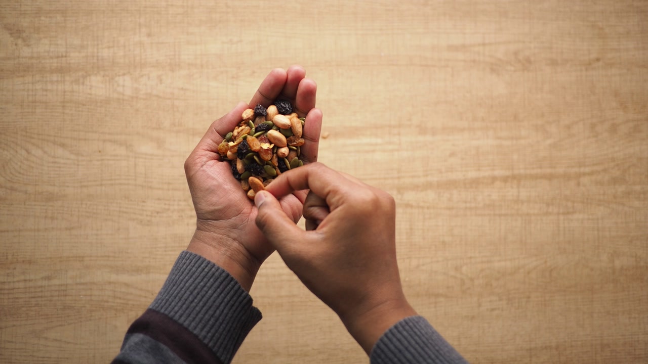 Person Picking Healthy Mixed Nuts and Dried Fruits from Hand