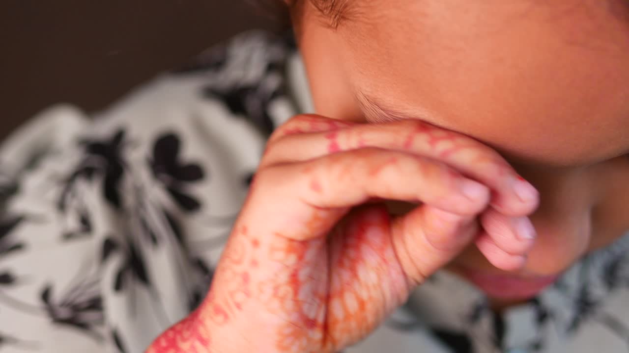 Ritratto ravvicinato di una ragazza carina con henné rosso sulla mano.