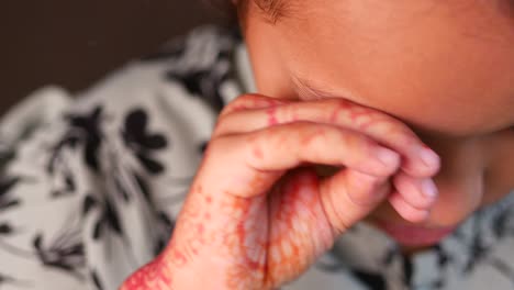 close up portrait of a cute girl with red henna on her hand