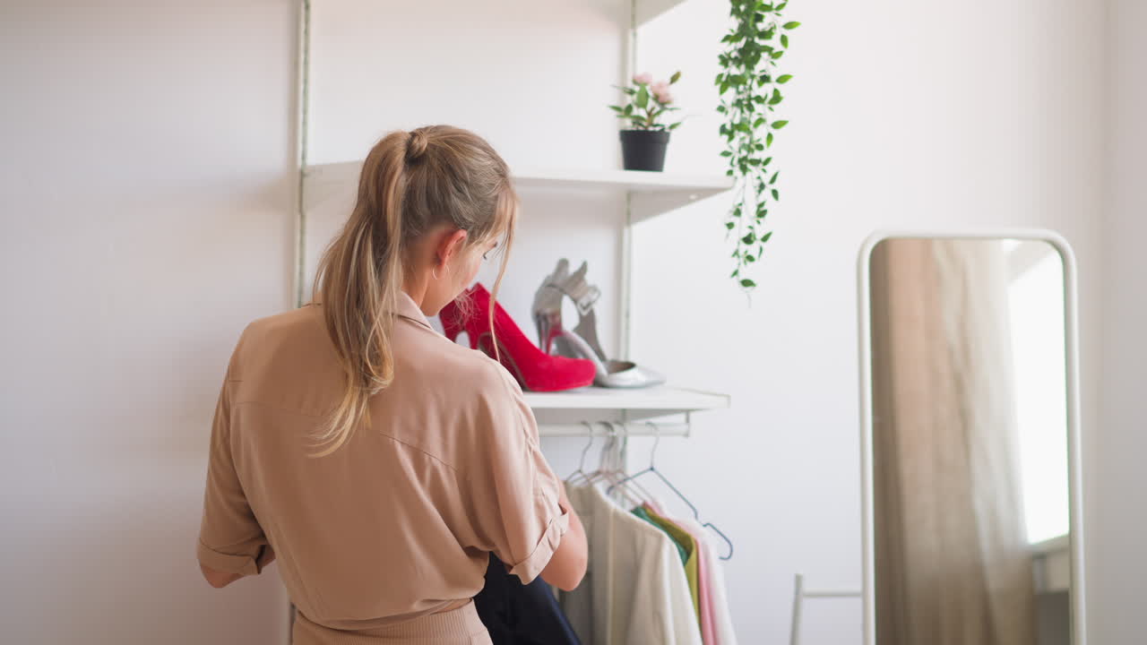 여자는 클래식한  ⁇  셔츠를 입고 옷을 선택합니다.