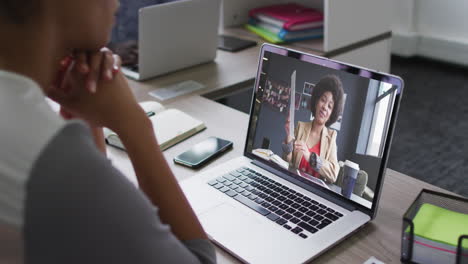 mid section of african american woman having a video call on laptop with female colleague at office