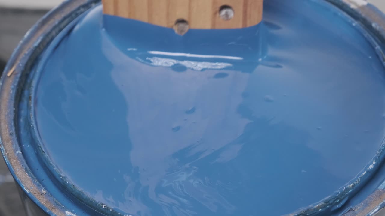 Close up of Wooden plank stirring blue paint