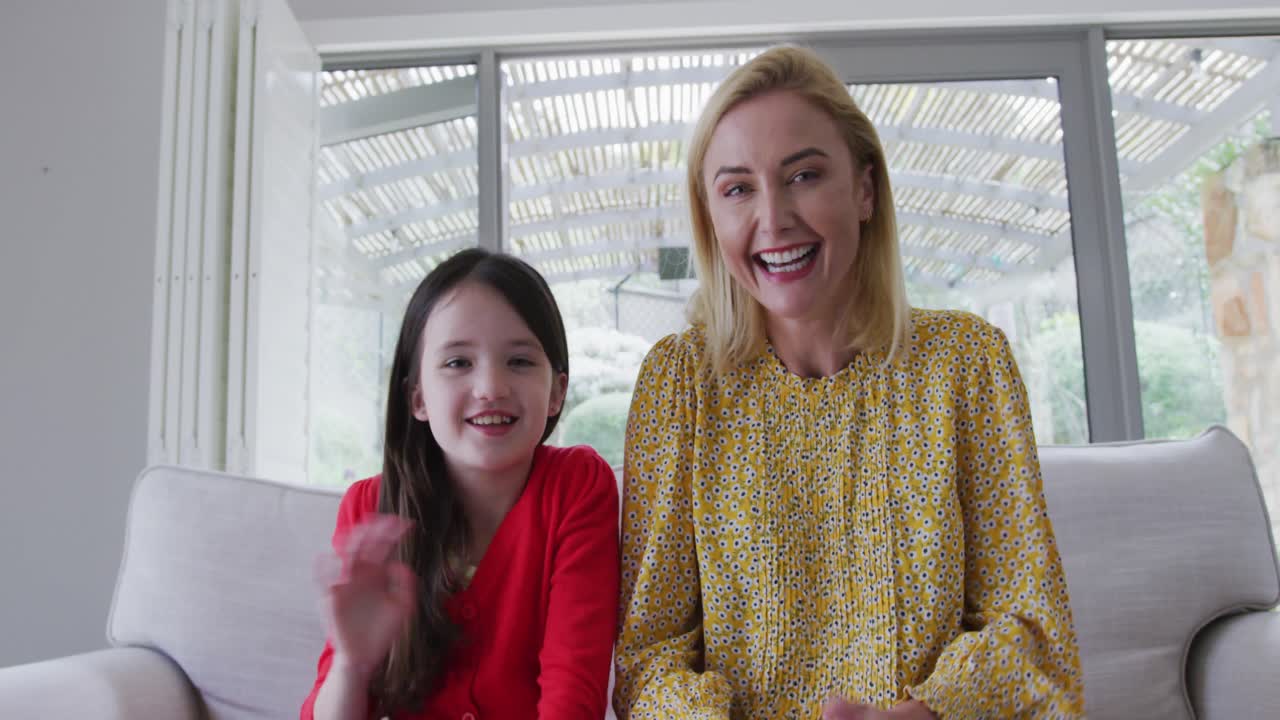 엄마와 딸이 카메라를 보면서 손을 흔들고 있다