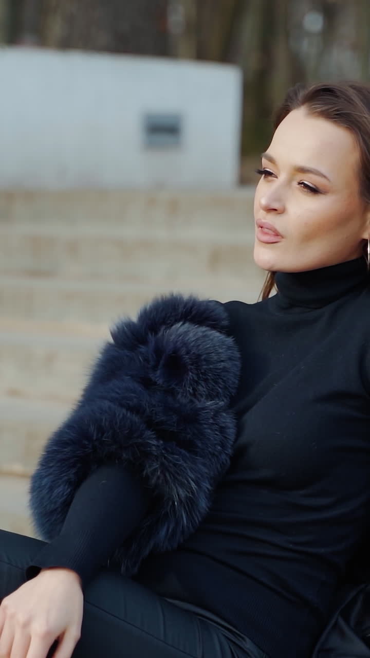 Sexy brunette woman posing wearing dark fur coat looking to tha camera with hands near face. Fashion video. Vertical video