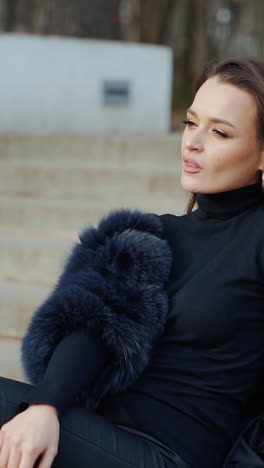 sexy brunette woman posing wearing dark fur coat looking to tha camera with hands near face. fashion video. vertical video