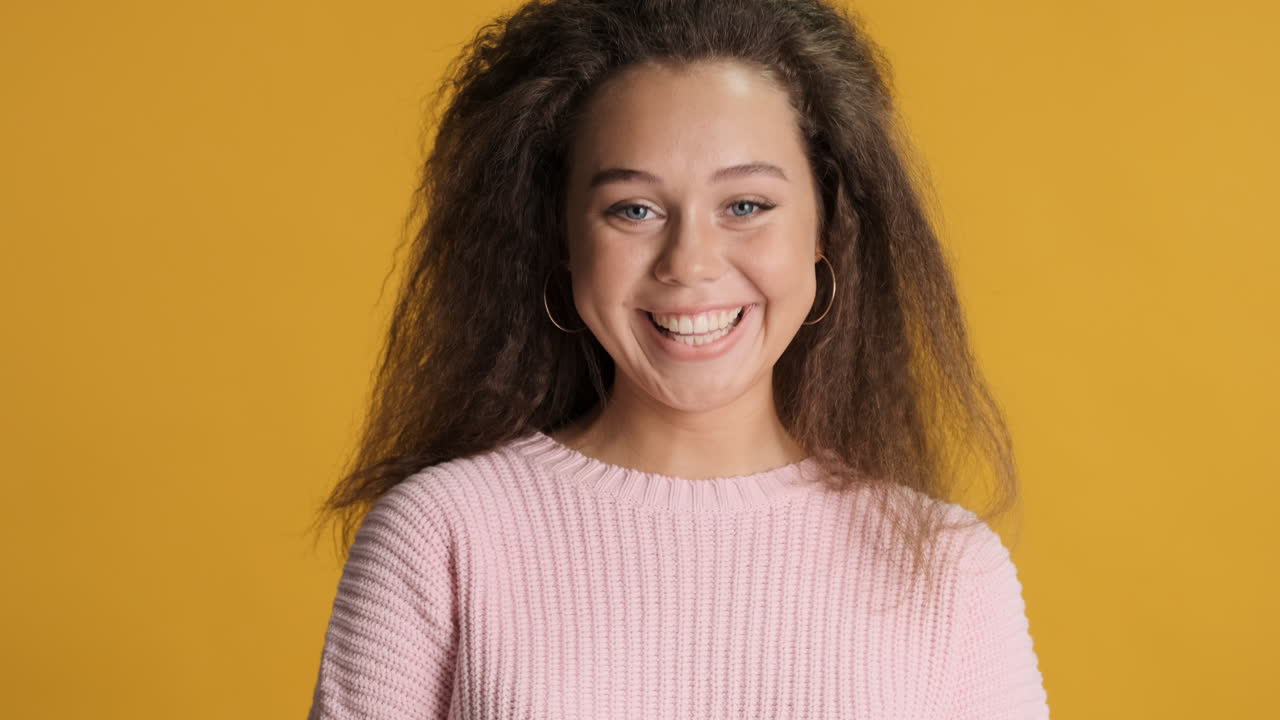 Caucasian curly haired woman smiling to the camera.