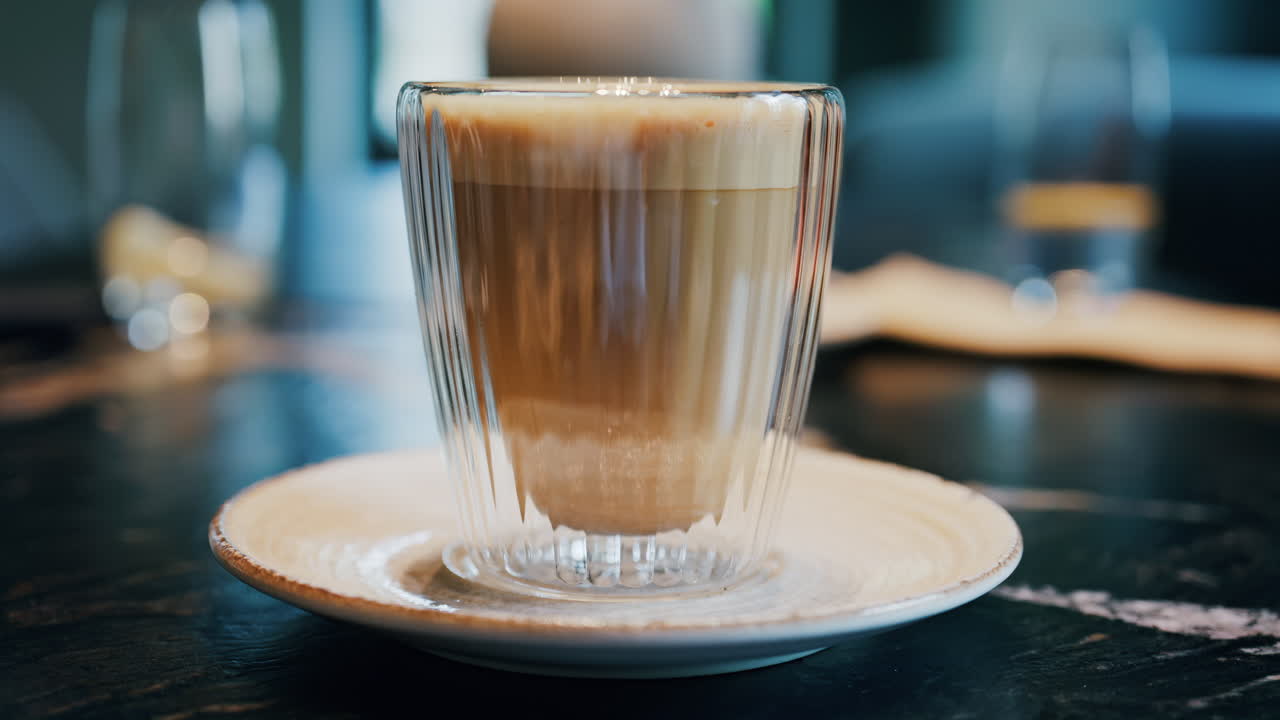 Close up of a glass cup with a latte at a cafe