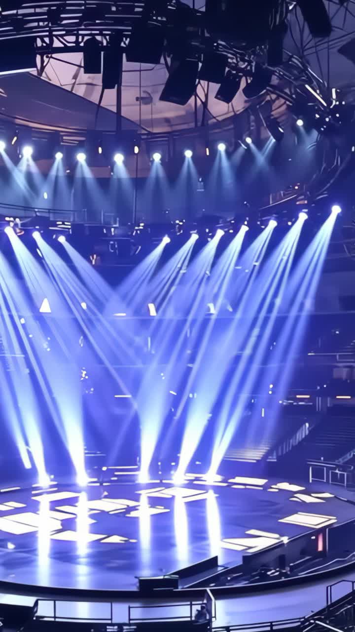 Vertical video: Circular stage undergoing lighting testing in arena, cycling moving head spotlights