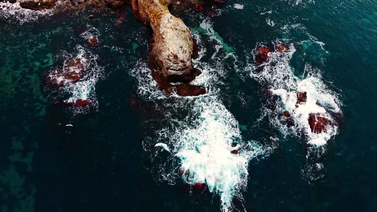 Aerial view of waves breaking on rocky outcrop. Overhead drone shot of turquoise sea, white foam and scattered boulder along Black Sea coast.