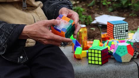 man solving rubik's cube with various puzzles