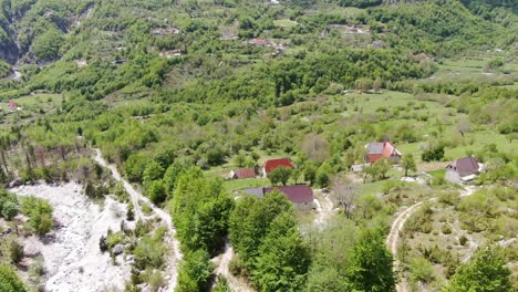 Drone-view-in-Albania-in-the-alps-flying-over-a-green-valley-with-small-houses-in-Theth