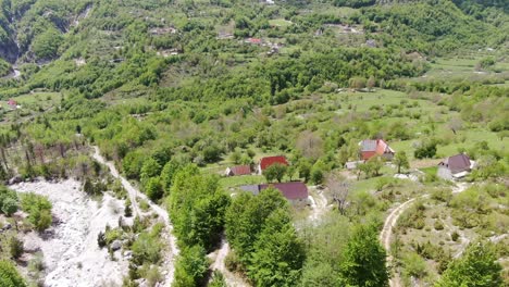 drone view in albania in the alps flying over a green valley with small houses in theth