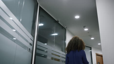 mujer de negocios afroamericana caminando con confianza en el pasillo de la oficina de la compañía.