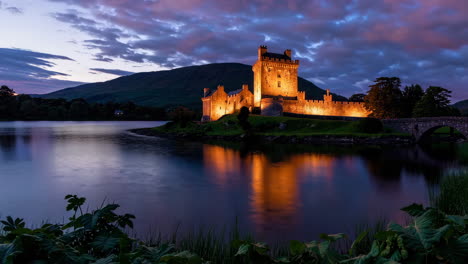 dunguaire castle illuminated at twilight reflecting on the water