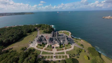 steady, slow flyover focusing on the magdalena palace’s rooftop and structure, with the sea visible in the background, highlighting architectural detail and coastal scenery