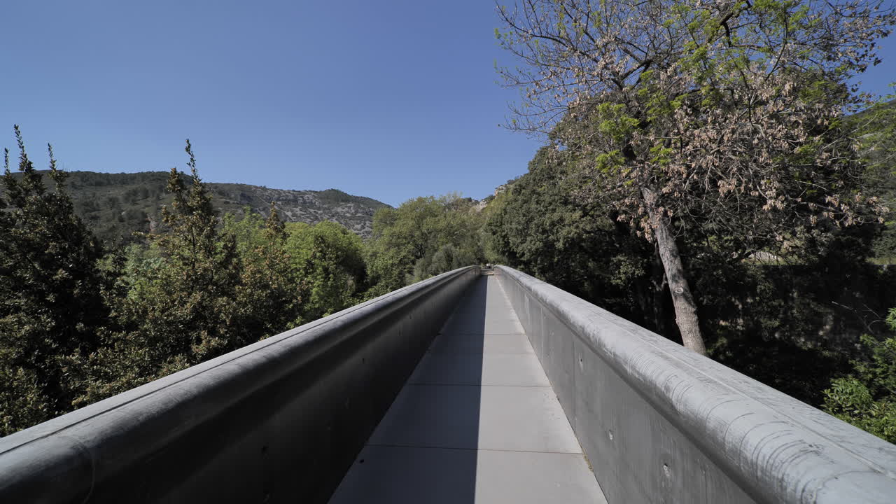 caminando por un estrecho puente gris vista en primera persona en el bosque al sur de francia