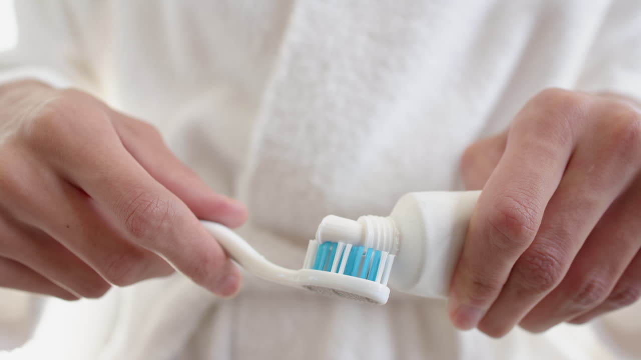 Applying toothpaste on toothbrush, person preparing for morning dental care routine