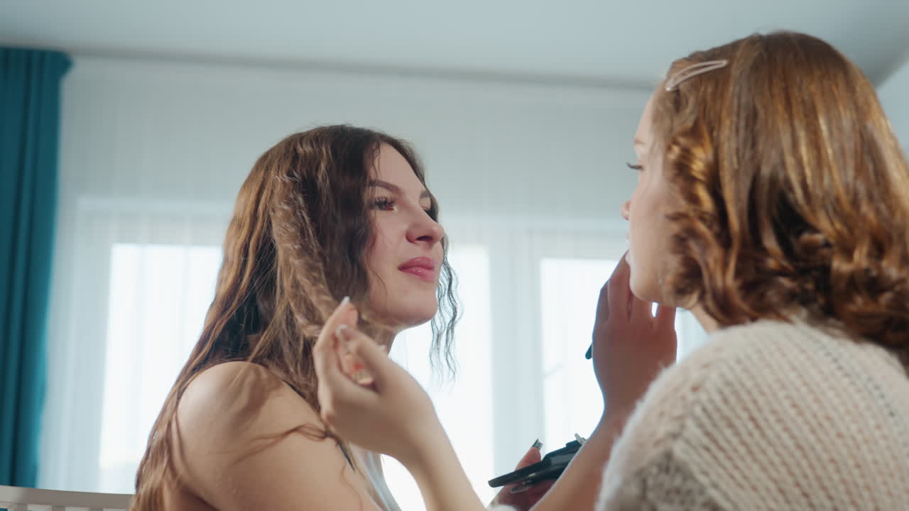 Woman Learns Makeup From Friend, Friend Teaches Makeup Skills To Woman In Natural Daylight Setting, Sunny Room Setting Where Woman Learns Makeup Application From Her Friend Comfortably