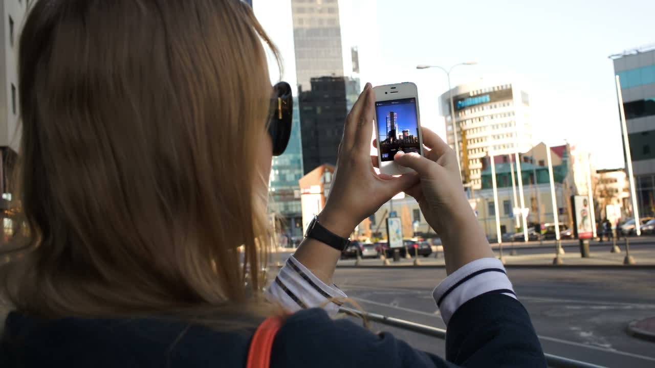 Mulher na cidade tirando fotos com seu smartphone