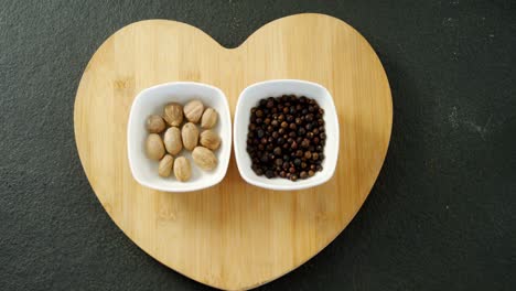 nutmeg and black pepper on heart shape board 4k