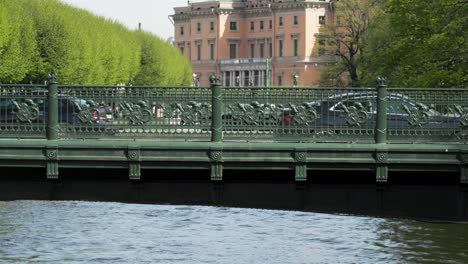 people and cars drive on the old bridge in the historic city, tourists walk around st. petersburg