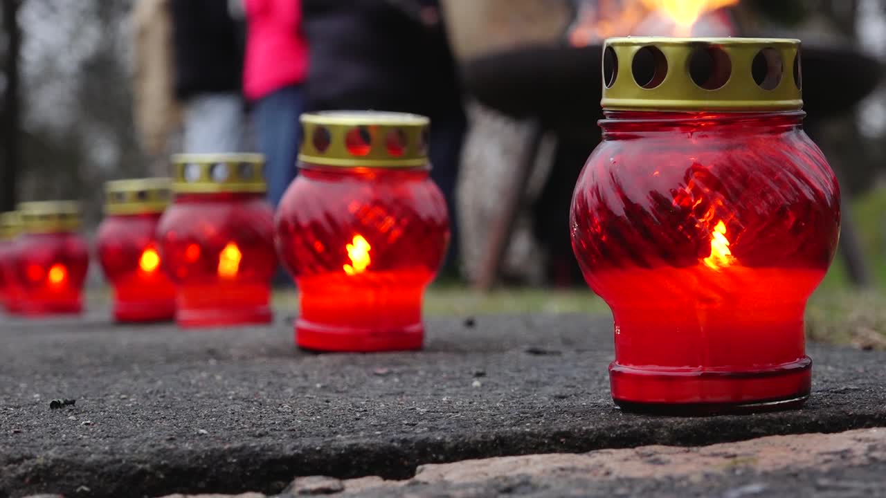 A solemn memorial with red and white candles surrounded by fresh flowers, symbolizing remembrance and tribute. A peaceful scene honoring loved ones or national commemorations.