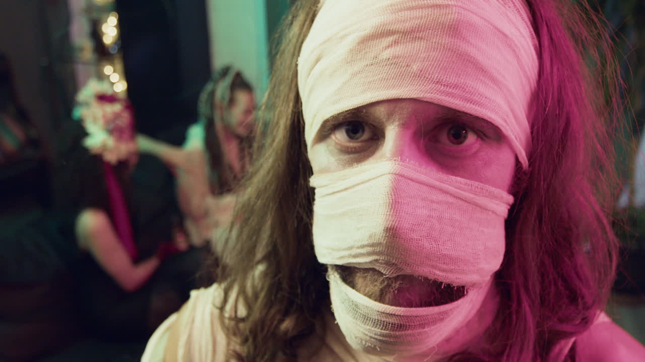 мужчина смотрит на камеру на вечеринке на хэллоуин.