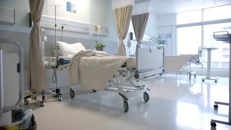 Sunny-hospital-room-with-beds,-plants-and-beige-curtains,-slow-motion