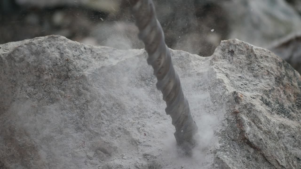 Close up of a starting driller digging a hole into a rock in slow motion