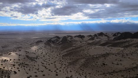 Drohnenschuss-Beim-Flug-über-Die-Dünen-Von-Tatón-In-Katamarca,-Argentinien-Bei-Bewölktem-Himmel-Mit-Lichtstrahlen-In-Der-Ferne