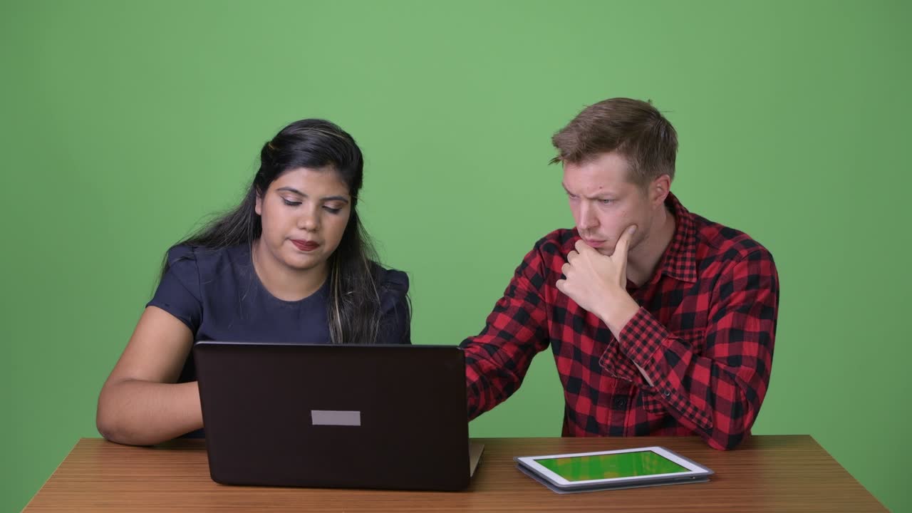 joven pareja de negocios multiétnica juntos contra un fondo verde