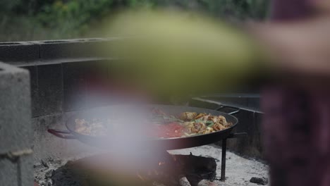 preparing traditional paella outdoors over a wood fire