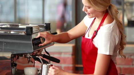 smiling barista steaming milk at the coffee machine