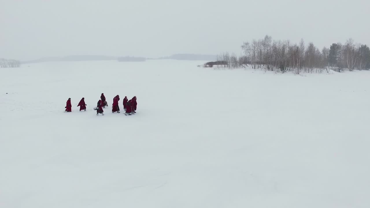 monjes caminando por un lago congelado en invierno