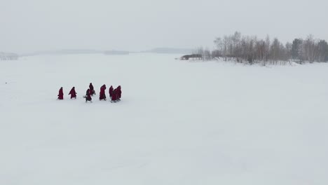 monks walking on a frozen lake in winter