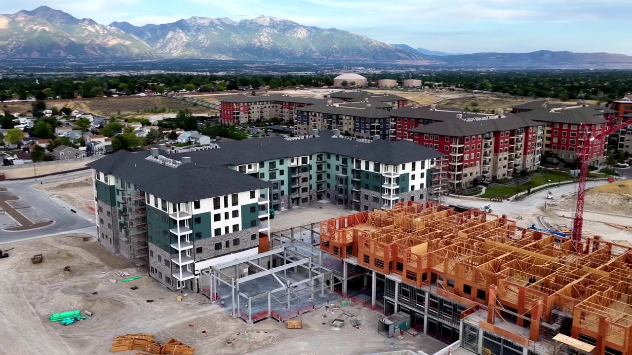 Costruzione di appartamenti con struttura in legno con gru a torre, edifici residenziali completati e lavori di sterro attivi a Taylorsville, Contea di Salt Lake, Utah, Valle di Salt Lake, Catena del Wasatch, orbita di drone