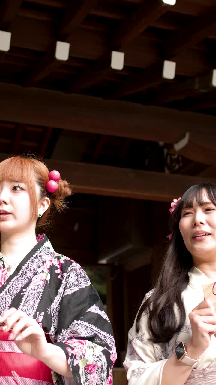 Deux jeunes femmes vêtues de kimonos traditionnels tiennent des plaques de prière en bois dans un sanctuaire shintoïste japonais.