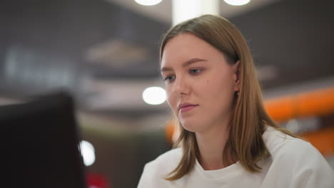 focused young freelancer working on laptop in modern mall environment, showcasing productivity, dedication, and a dynamic workspace with blurred vibrant lighting and abstract background