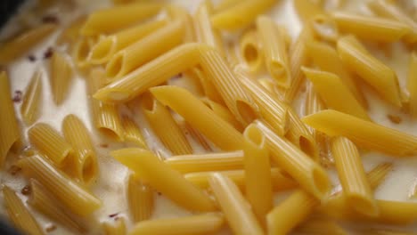 cocinero añadiendo crema a la pasta hirviendo