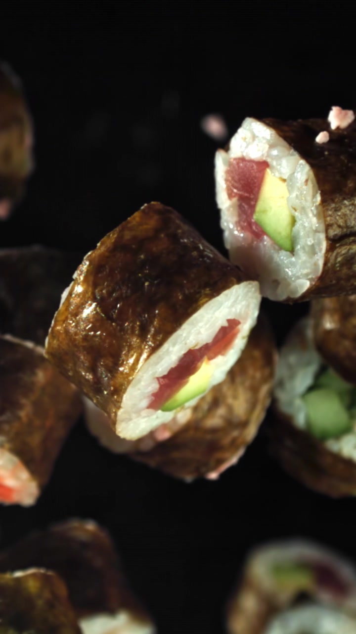 Tuoreita sushimaki-rullia putoaa hidastettuna mustalla taustalla