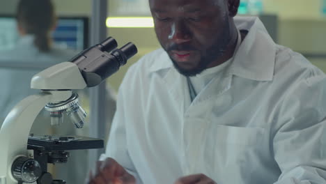 african american scientist using microscope in laboratory